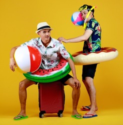Two young Asian boys in summer costume laugh as enjoy playing fun outdoor game with ball float, donut tube, and snorkel at swimming pool party as family recreation to relax on vacation of hot season.