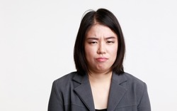 Portrait studio isolated cutout closeup head shot of Asian young moody sad upset unhappy stressed depressed frowning face female businesswoman in formal suit jacket look at camera on white background.