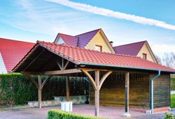 Wooden carport with red brick roof on a new house.