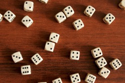 Dice are scattered on a wooden table. Cubes lie in random order. Slight blur.