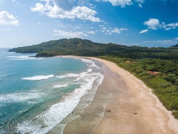 Costa Rica Best Beach: Playa Grande, Guanacaste - Aerial Drone View of Tropical White Sand Beach - Famous Surfing Location with big Waves, lush green Mountains, blue Sky and beautiful Landscape.