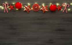 A string of red christmas decorations, lights and candy sticks, on a destressed dark woodern background