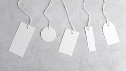 Round tag mockup, rectangle tag mockup, strip tag mockup with white cord, close up. Various price cardboard labels on grey background. Blank empty paper product tags, sale and black friday concept