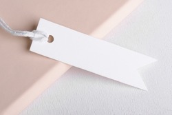 Rectangle strip white gift tag mockup with white cord, close up on beige and white background. Blank paper rectangular price tag mockup, Sale and Black Friday concept, element for design, label mockup