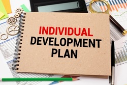Closeup on businessman holding a card with text INDIVIDUAL DEVELOPMENT PLAN, business concept image with soft focus background and vintage tone