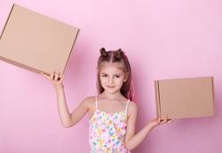  Little girl with two parcel box isolated on pink.  Little girl playing with  boxes.  Beautiful childe with cardboard boxes.