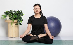 Young attractive smiling woman practicing yoga, wearing sportswear, pants and top, indoor full length at home