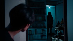 A man looking at scariest Thai lady ghost across the room staring at him.The lady ghost is completely in silhouette.