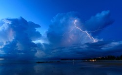 Lightning from a cumulonimbus thunder cloud strikes a tropical beach