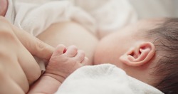 Close up baby hand holding mom fingers, mother breastfeeding newborn baby infant nursing and feeding Baby, feeling love in touch, maternity, healthcare, breastfeeding, motherhood, childhood concept	
