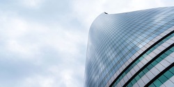 Low angle view at modern glass curved building with sky at background. space for text