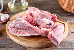 Frozen pork meat on a cutting board. Frozen pork bones. Frozen food