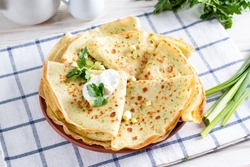 Thin pancakes with herbs. Salty Pancakes with green onions. Wood background. Delicious food for a bite to eat. Traditional Russian pancakes for Maslenitsa.