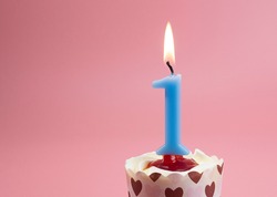 Number 1 Burning birthday celebration candles in a cupcake isolated on pastel pink background, Front view Blank for design copy space.
