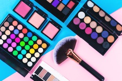 Makeup and beauty products on pink and blue background. Eye shadow palettes. fan contouring brush and blushes. Flatlay, top view. 