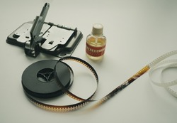 Vintage 8mm moviola cutter with 8mm reel and glue on white background.
