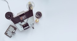 Vintage 8mm moviola with cutter, 8mm reel and glue on white background.
