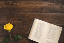 Romantic concept. Open book with poems and rose, on wooden background. Flat lay, top view, copy space.