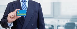 Cropped image of businessman holding plastic credit card with printed flag of Aruba. Background blurred.