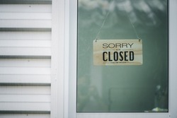 Sorry we're closed sign. grunge image hanging on a  glass door.