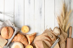 Homemade breads or bun, croissant and bakery ingredients on white wood background, breakfast food concept top view and copy space