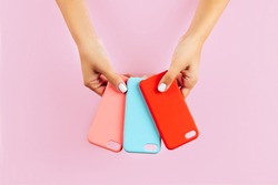 hands holding colorful smartphone cases. Pink Background