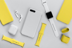 Stylish smart watch, phone, earphones and cases on gray background