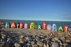 Happy Birthday with multicolored stones on the beach 