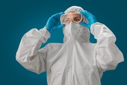 Scientist or Medical staff wearing personal protective gown or PPE, white N95 mask and blue medical gloves puts on goggles. Personal protective equipment to protect against coronavirus covid-19.