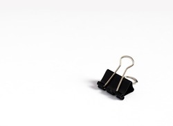 An image isolated binder clip black color stationery paper for office paperclip on the white background with copy space for text.