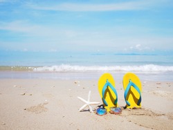 Close up Yellow sandal sunglasses and white starfish on the beach over sea background. Summer holiday concept.