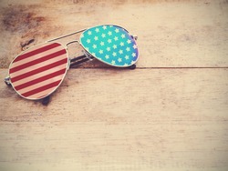 mirror sunglasses with american flag pattern on wooden background.4th of July concept. Vintage filter effect. Happy flag day.