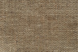 Burlap fabric texture macro. Background of coarsely woven sackcloth from jute, hemp or flax. Design element for rustic country style. Brown tan сanvas cloth as craft material. Top view.