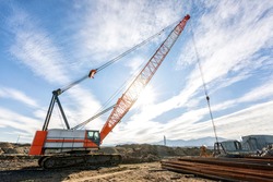 Wide angle view of the big crawler crane in the construction site. A crawler crane has its boom mounted on an undercarriage fitted with a set of crawler track that provide both stability and mobility.