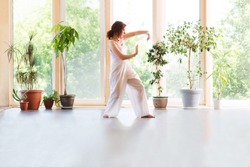 Young Woman praticing tai chi chuan in the home. Chinese management skill Qi's energy.