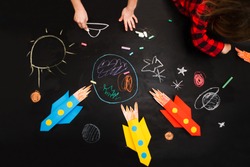 the child draws a rocket and space on a blackboard. preschool Child in creativity in the home.