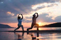 Man and woman doing Tai Chi chuan at sunset on the beach.  solo outdoor activities. Social Distancing. Healthy lifestyle  concept. 