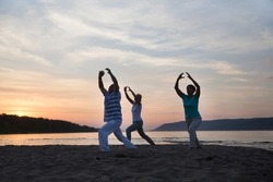 group of people practice Tai Chi Chuan  at sunset on the beach.  Chinese management skill Qi's energy.