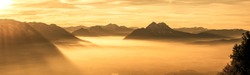 wide angle panorama from mt. gaisberg in salzburg, overlooking salzburg covered by fog during golden hour