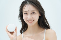 A woman with a smile and skin care item