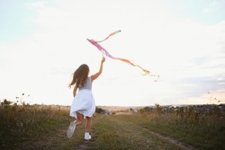 one happy little girl running on field with kite