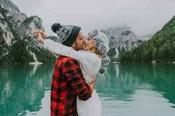 Beautiful couple of young adults visiting an alpine lake at Braies, Italy - Tourists with hiking outfit having fun on vacation during autumn foliage - Concepts about travel, lifestyle and wanderlust