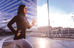 Muslim urban runner training in the city center. Beautiful woman doing sport in the early morning