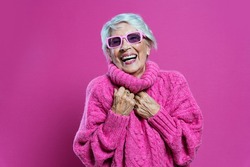 image of a beautiful and elegant old influencer woman. Cool grandmother posing in studio wearing fashionable clothes. Happy senior lady celebrating and making party. Concept about seniority 