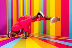 Beautiful african american young woman dancer having fun inside a rainbow box room - Cool and stylish adult woman portrait on multicolored background, influencer creating content for social networks