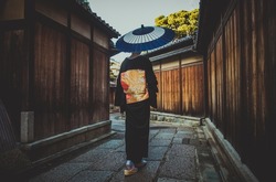 Beautiful japanese senior woman walking in the village. Image of an old person wearing japanese traditional kimono and umbrella  spending the morning in Kyoto. Concept about kaizen and cultures