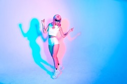 Young woman with pink hair dancing and having fun. Colored gel portraits with futuristic outfit