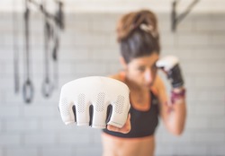 fighter woman fist close up. straight focus on the glove with the rest of the image on blur. concept about sport and people