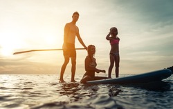 surfing. happy family silhouette on the paddle board. concept about family, sport and fun