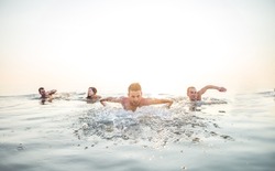 Group of friends swimming in the sea - Cheerful people having fun and enjoying summer vacation